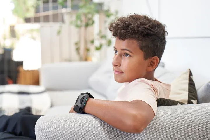 A child relaxing on a couch while wearing a wrist-worn haptic vibration wearable